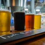 Row of colorful craft beers served on a wooden tasting board