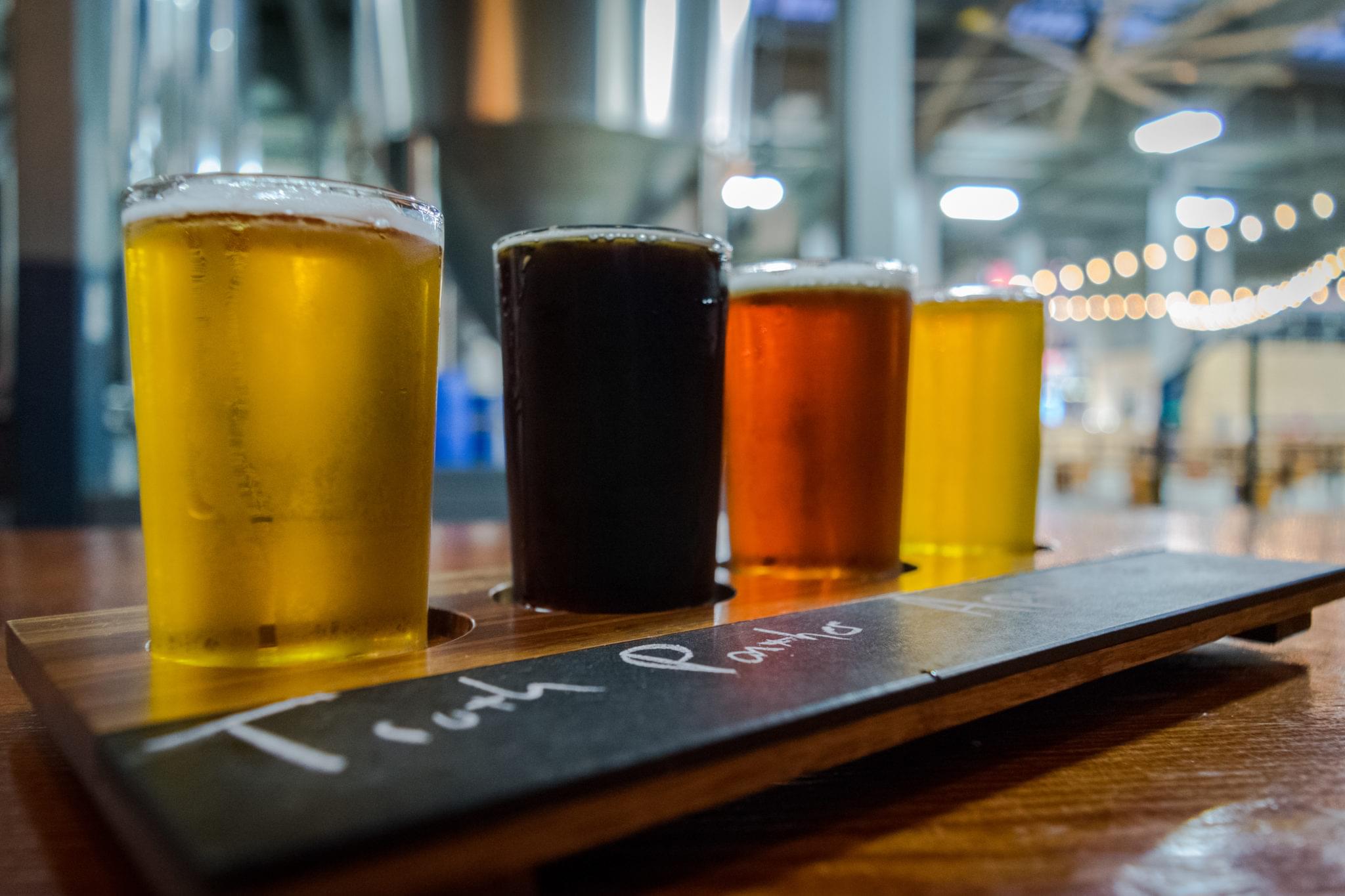 Row of colorful craft beers served on a wooden tasting board