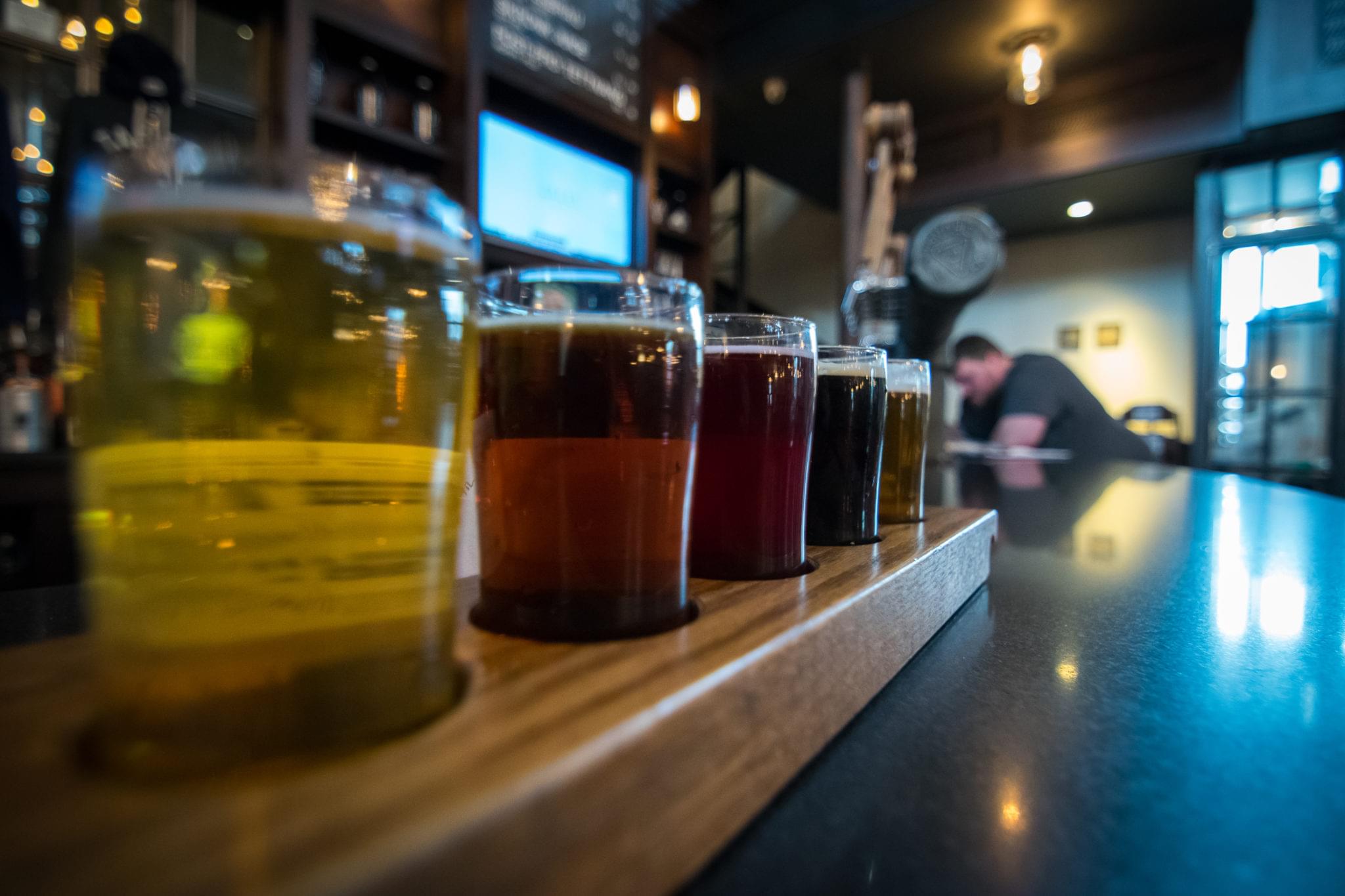 Craft beer flight lineup on a wooden brewery bar counter