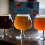 Two craft beers served in stemmed tasting glasses on bar counter