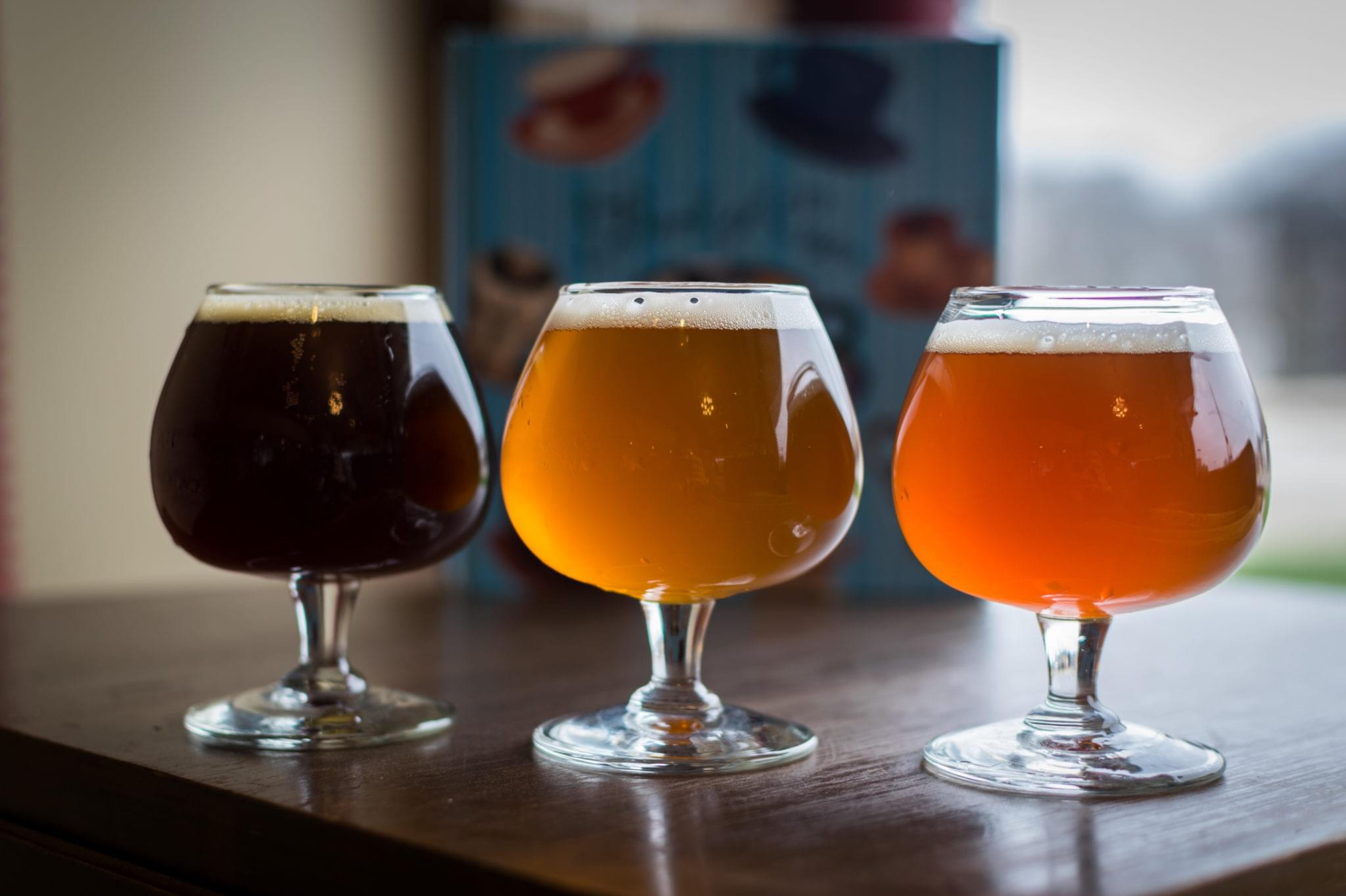 Two craft beers served in stemmed tasting glasses on bar counter