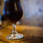 Dark craft beer served in a stemmed glass on a wooden table